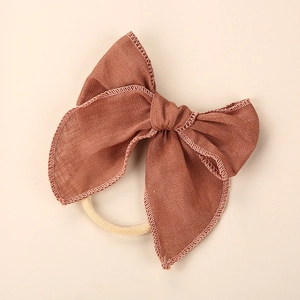 Close-up of a reddish-brown linen bow headband for girls with fine textured stitching