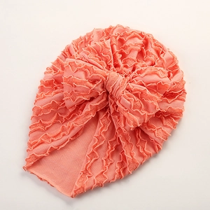 Detail von korallenfarbenem Baby-Turban-Hut mit Rüschendetails und großer Schleife