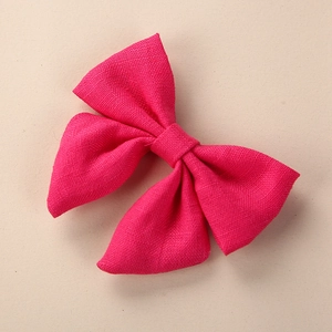 Macro detail of magenta pure linen hand-knotted bow hair clip with visible fabric texture