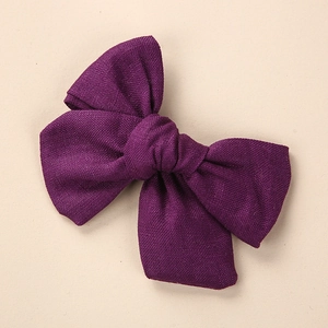 Détail de la texture en lin d'une pince à cheveux à nœud violet foncé pour filles