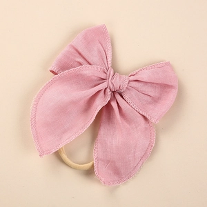 Close-up of pink linen bow headband with soft fabric texture and elastic band