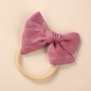 Close-up of dark pink linen bow headband with high-elastic beige nylon band for babies