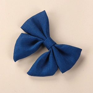 Close-up of dark blue linen hair clip showing the detailed fabric texture and handmade bow