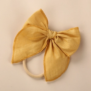Close-up of mustard linen bow headband with elastic nylon band and detailed stitching