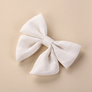 Close-up of a handmade cream linen bow hair clip showing detailed woven fabric texture