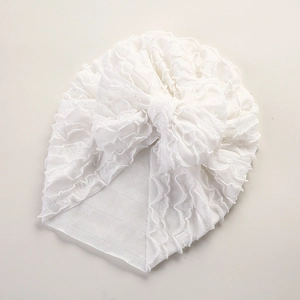 Detail der weißen gerippten Baby-Turban-Mütze mit Rüschenstruktur und großer Schleife