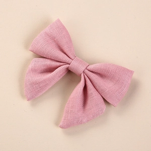 Close-up detail of soft pink linen fabric texture on handmade bow hair clip for girls
