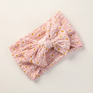 Detailed view of pink baby headband featuring daisy floral print and a soft ribbed bow