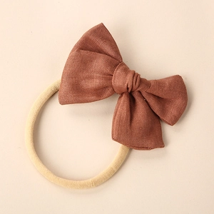 Detailed macro view of dark brown linen bow knot on a soft beige elastic baby headband