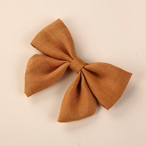 Detailed macro view of the coarse linen texture on the mustard yellow handmade hair bow clip