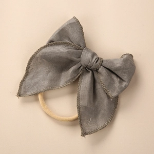 Detail of grey linen bow headband featuring textured fabric and elastic nylon band
