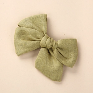 Détail de la texture en lin vert olive d'une grande barrette à nœud pour bébé