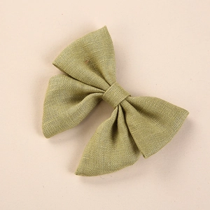 Detailed close-up of grass green linen fabric kids hair bow with rustic hand-tied texture