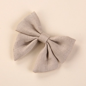Macro shot of light linen hand-knotted bow hair clip showing detailed fabric texture