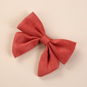 Close-up of handmade red linen bow hair clip showing fabric texture and design