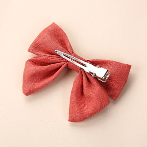 Handmade linen bow hair clip for girls in rustic reddish orange with a metal alligator clip
