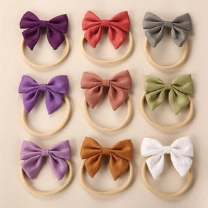 9-piece set of linen bow headbands for babies in assorted solid colors on nylon bands