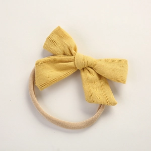 Detail of ginger cotton bow with hollow lace edges on soft nylon baby headband