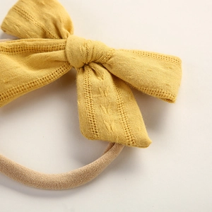 Detailed macro of yellow cotton bow headband with delicate floral cutout pattern