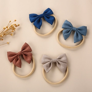 Close-up of four linen bow headbands in dark blue, grey, and brown with soft nylon bands