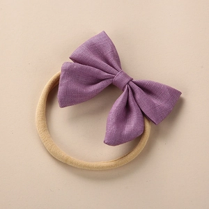 Detail of the linen texture on a soft purple baby bow with a beige elastic headband