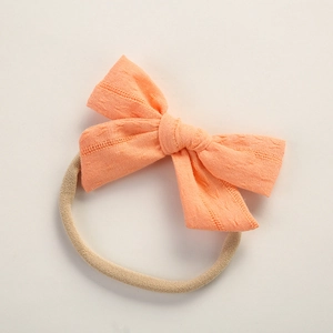 Detail of soft cotton baby headband with light orange bow and elastic nylon band