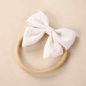 Detail of linen bow headband with textured weave on a high-elastic nylon band for infants
