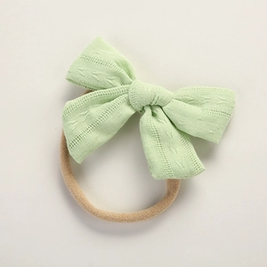 Detail of light green cotton bow headband with embroidered texture for babies
