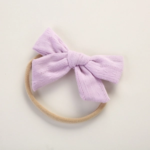 Detailed macro view of light purple knitted cotton bow on soft elastic baby headband