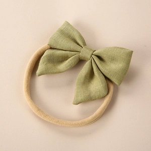 Detailed view of green linen bow on soft elastic headband for infants and babies
