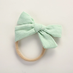 Close-up of mint green jacquard cotton bow with seamless nylon headband for babies