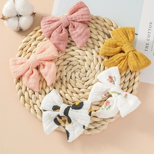 Détail de cinq barrettes à nœuds en coton avec motifs floraux et léopard sur tapis tressé
