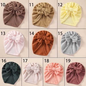 Grid display of baby waffle knit turban hats with large bows in ten different soft colors