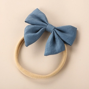 Detailed macro view of denim blue linen bow hair tie with seamless elastic band