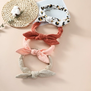 Close-up of four textured cotton rabbit ear headbands in leopard and solid neutral tones