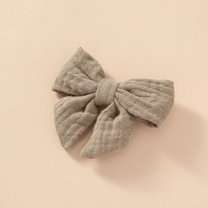 Gros plan d'une pince à cheveux en mousseline de coton avec texture tissée beige doux