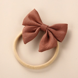 Detail shot of brown linen bow texture on a soft beige elastic nylon baby headband