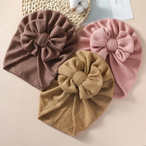 Detailed waffle knit texture on baby bow hats in brown, pink, and yellow colors