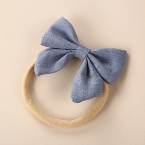 Close-up of blue linen fabric bow headband for babies with clear texture and elastic band