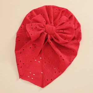 Detail of red baby turban hat with hollow eyelet embroidery and a large bow
