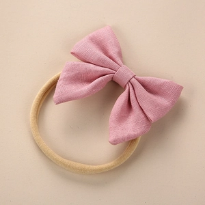 Detail showing pink linen bow attached to a high-elastic beige nylon baby headband