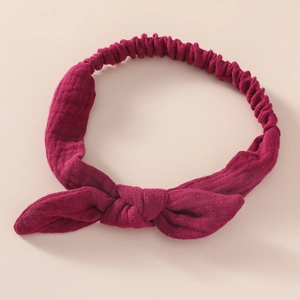 Detail of burgundy cotton baby headband featuring a knotted bow and elastic back band