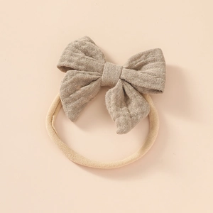 Detail of soft cotton baby headband showing natural linen bow and seamless nylon band