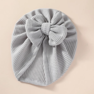 Close-up detail of a soft grey waffle knit texture on a newborn baby bow hat