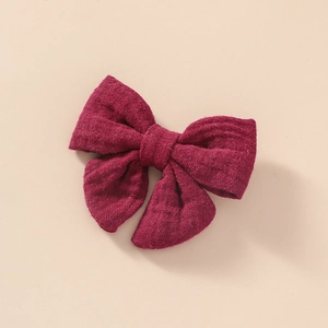 Détail de la pince à cheveux en mousseline rouge foncé montrant le tissu doux