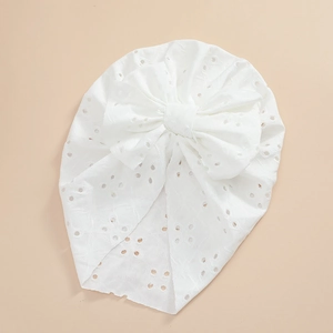 Detailed macro view of pure white baby lace turban with intricate floral embroidery and bow