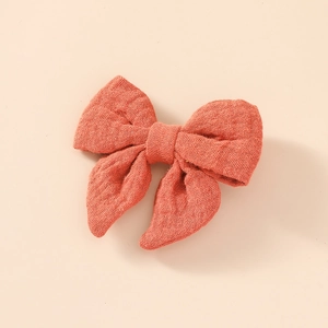 Gros plan d'un nœud à cheveux en coton mousseline rouge corail avec texture de tissu