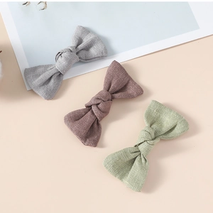 Vue détaillée de trois pinces à nœuds en lin dans les tons gris, mauve et vert