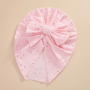 Detailed view of pink baby turban hat featuring eyelet knit fabric and a large bow