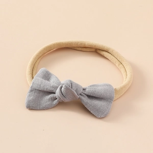 Détail d'un nœud en lin gris sur un bandeau souple en nylon pour bébé et texture